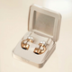 The gold Nova H1 Audio Earrings in their jewelry box-shaped charging case.